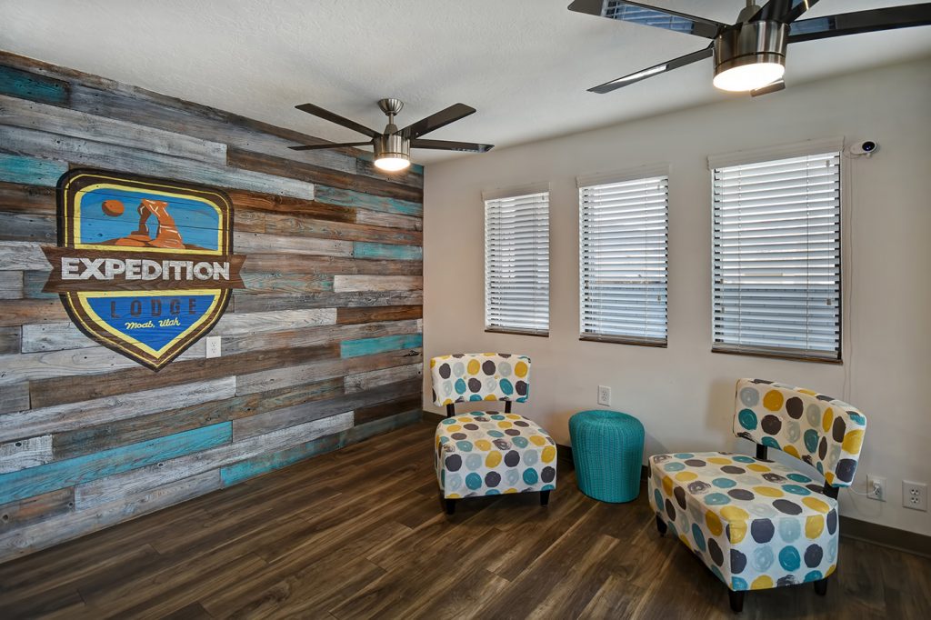 Expedition Lodge Moab lobby with two chairs and a painted Expedition Lodge logo on the wall, creating a welcoming entrance for guests near Arches National Park.