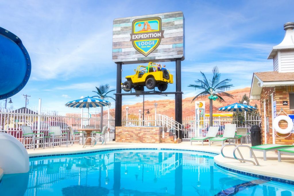 Expedition Lodge Moab sign with lifted yellow Jeep underneath, next to the outdoor pool, symbolizing a welcoming landmark near Arches National Park.