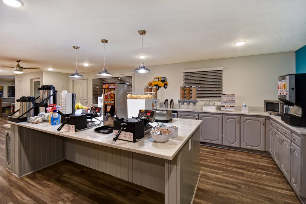 Breakfast area at Expedition Lodge Moab with waffle irons, cereal dispensers, coffee carafes, and various breakfast options, providing a convenient start to the day near Arches National Park.